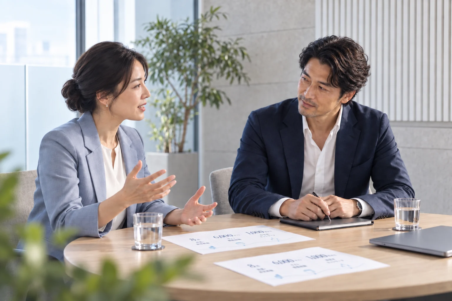 相談の机上に実績図の資料が置かれたAI生成イメージ