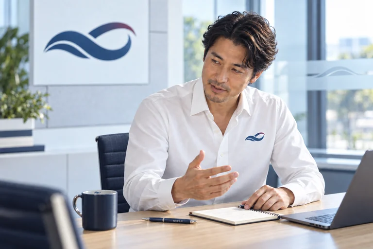 白いワイシャツの胸元に会社のロゴ。